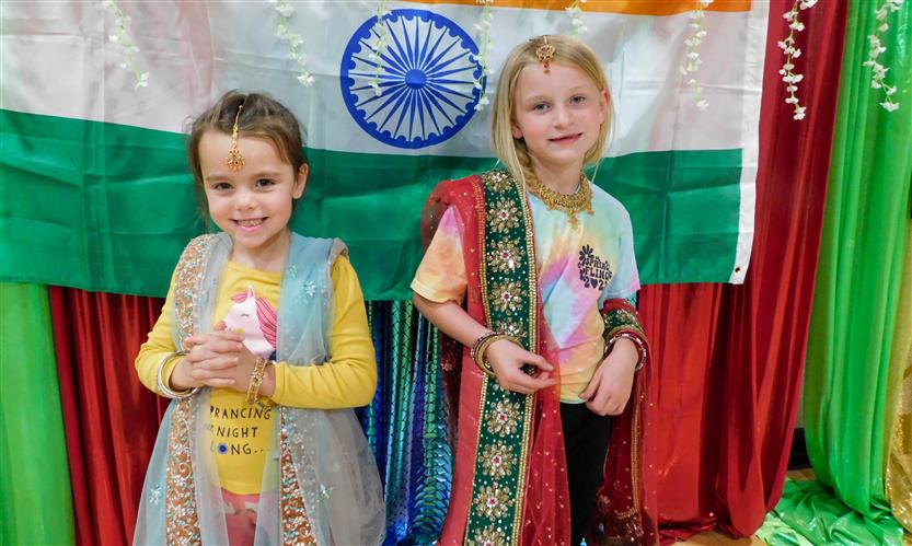 Two students stand in front of a green and red backdrop